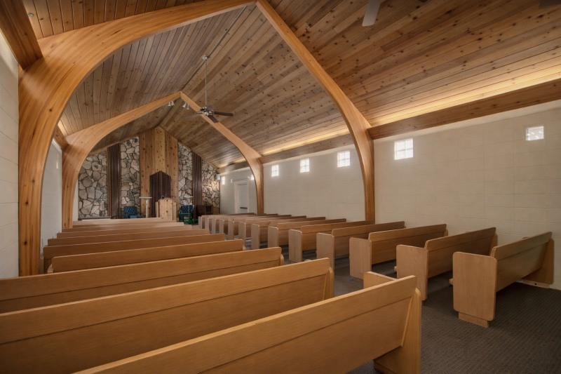 Direct Cremations Apache Junction, AZ chapel with wood pews, arched beams and stone feature front wall.