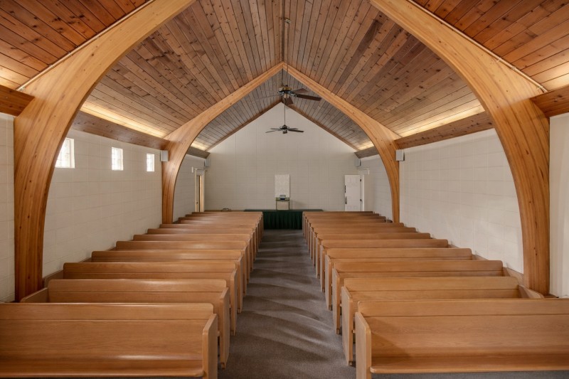Direct Cremations Mesa, AZ chapel interior with wooden pews, arched beams and vaulted wood ceiling.